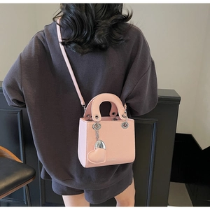 Detailed view of pink mini crossbody bag with heart pendant and lychee leather texture