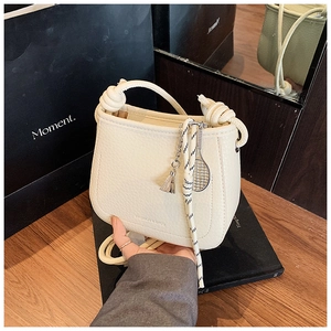 Detail shot of beige mini bucket bag with lychee texture and metal tennis racket charm