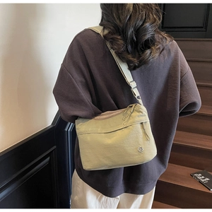 Detail of light green nylon tote bag featuring adjustable strap and metallic logo accent