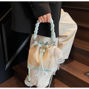 Detail of woven straw bucket bag with blue leather handle and white lace bow accessory