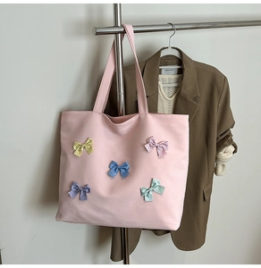 Detailed view of pink plaid tote bag with colorful decorative polka dot bows on front
