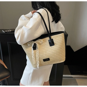Détail du sac cabas en paille tissée avec nœud en dentelle blanche et fines anses noires