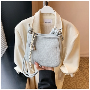 Detail of light blue lychee leather bucket bag with knot strap and silver tassel pendant