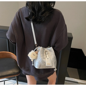 Detail of silver snakeskin textured bucket bag with fluffy white pompom charm