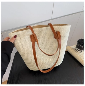 Detalle del bolso tote de paja tejida con correas de cuero marrón y costuras finas