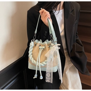 Detail of woven straw bucket bag with mint green leather trim and pearl lace ribbon