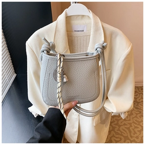 Detail of grey lychee leather bucket bag with tennis racket charm and rope strap