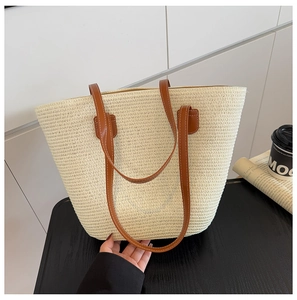 Detalle del bolso tote de paja tejida con correas de cuero sintético marrón y costura