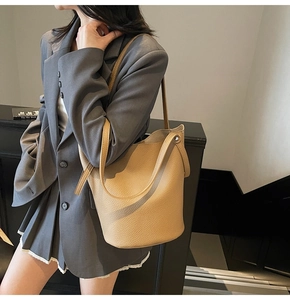 Minimalist camel pebble leather bucket bag shown as a shoulder carry on model