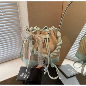 Detail of woven straw bucket bag with blue leather trim and pearl bow charm