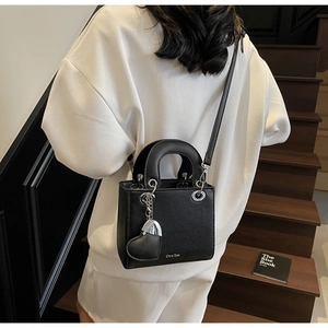 Litchi pattern black mini leather handbag with heart charm shown on model in stair scene