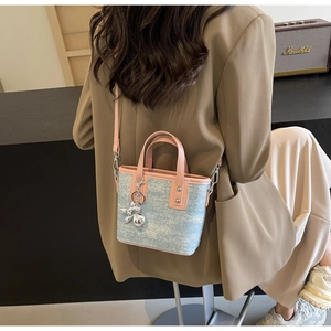 Detail of color-block bucket bag with pink leather handle and silver dog charm