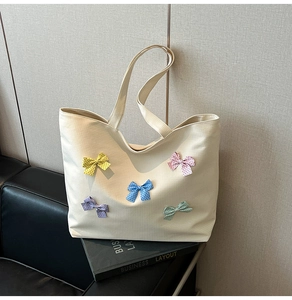 Detail view of cream canvas tote bag with five colorful polka dot bows on front