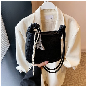 Detail of black lychee grain leather bucket bag with knot handle and tennis racket charm