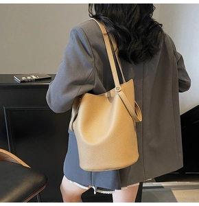 Detailed view of camel leather bucket bag with litchi grain and double handles