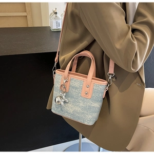 Detail of pink and blue contrast tote bag featuring a metallic balloon dog charm