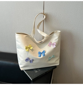 Close-up of cream canvas tote bag featuring colorful polka dot bows and plaid texture