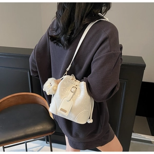 Detail of white bucket bag with snake pattern embossing and plush sheep pendant