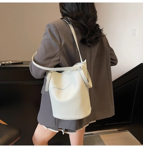 Detail of lychee pattern cream shoulder bag featuring adjustable strap and metal hardware