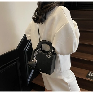 Detail of black lychee grain handbag with silver heart charm and Chrs'2an logo