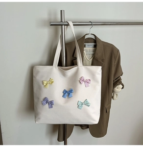 Detail of colorful bow decorations and textured canvas on a large white tote bag
