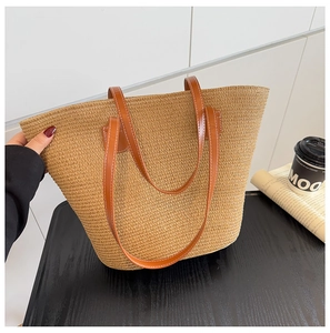 Detalle de bolso tote de paja de mano con asas de cuero marrón y textura tejida