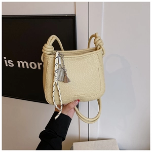 Close-up of beige lychee grain bucket bag with knot handle and tennis racket charm