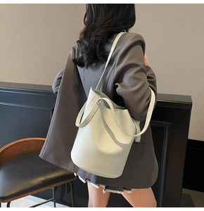 Detailed macro shot of creamy white lychee grain leather on a stylish bucket bag