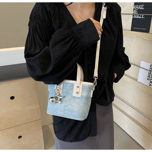 Detail of light blue denim mini tote with cream trim and silver balloon dog charm