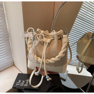 Detail of cream woven straw bucket bag with white leather trim and pearl heart charms