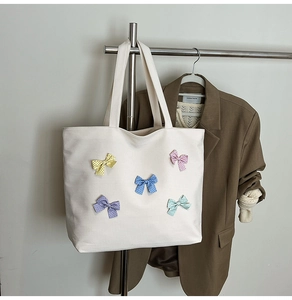 Detail of white checkered canvas tote featuring five colorful polka dot bows for women