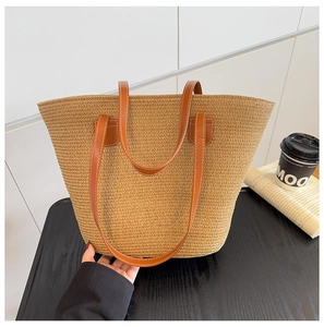 Detalle del bolso de paja tejida con asa de cuero marrón y costuras de contraste para el verano