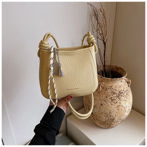 Detail of light yellow lychee grain leather bucket bag with unique knotted handle