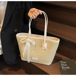 Détail d'un sac cabas en paille crème avec glands en dentelle blanche et anses en cuir