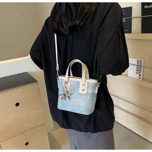 Detail of light blue denim texture crossbody bag with silver balloon dog pendant charm