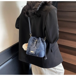 Detail of blue python-pattern bucket bag featuring drawstring closure and fuzzy charm