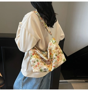 Detail of cute beige tote bag with 3D knitted bears and flowers on shoulder strap