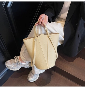 Detail of beige bucket bag featuring lychee texture and decorative V-shaped stitching