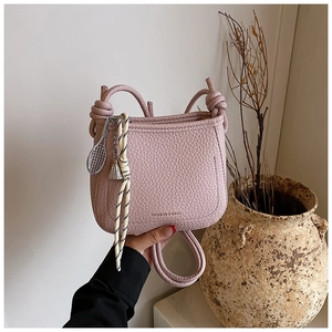 Detail of pink lychee grain bucket bag with tennis racket charm and knotted strap