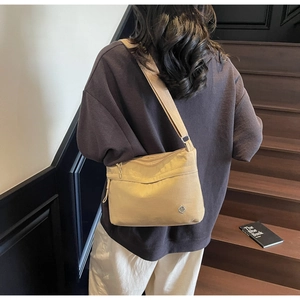 Detail of khaki crossbody tote bag with multi-pocket design and adjustable strap