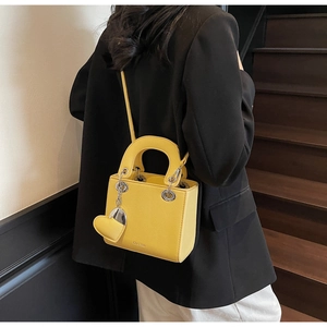 Detail of yellow lychee grain leather mini bag with metal eyelets and heart charm