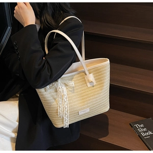 Détail du cabas en paille avec bandoulière en cuir blanc et nœud en dentelle élégant