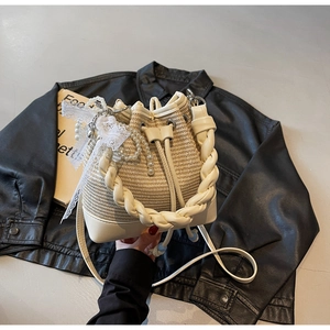 Detail view of woven bucket bag with leather handle and decorative pearl lace pendant
