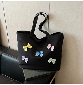 Detail of black canvas tote bag featuring five colorful 3D bowknot decorations