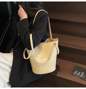 Detail of light yellow lychee pattern leather bucket bag with metal rivet accents