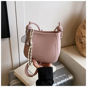 Detail of mauve bucket bag with tennis racket charm, fringe, and striped silk scarf wrap