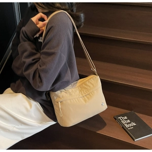 Detail of light khaki nylon shoulder bag with metal logo on high-quality model scene
