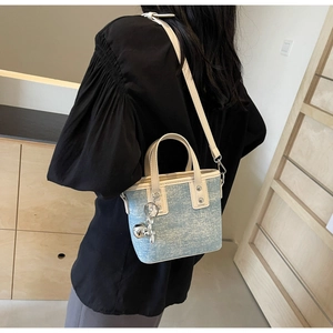 Detail of light blue denim mini tote with silver cat charm and white leather trim