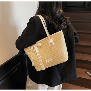 Détail du sac cabas en paille tissée avec nœud en dentelle blanche et bandoulière
