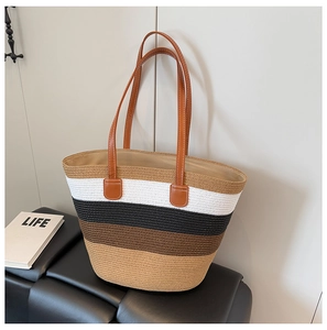 Detalle del bolso tote de paja tejida con rayas multicolores y asas de cuero marrón